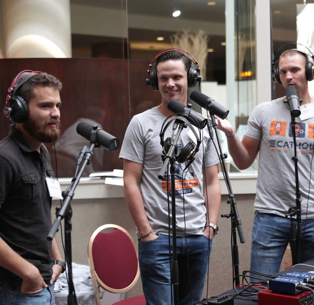 David, Adam, and another speaker engaged in discussion at a recording table.